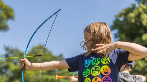 A girl wearing a black tee-shirt shooting an arrow with a plastic bow